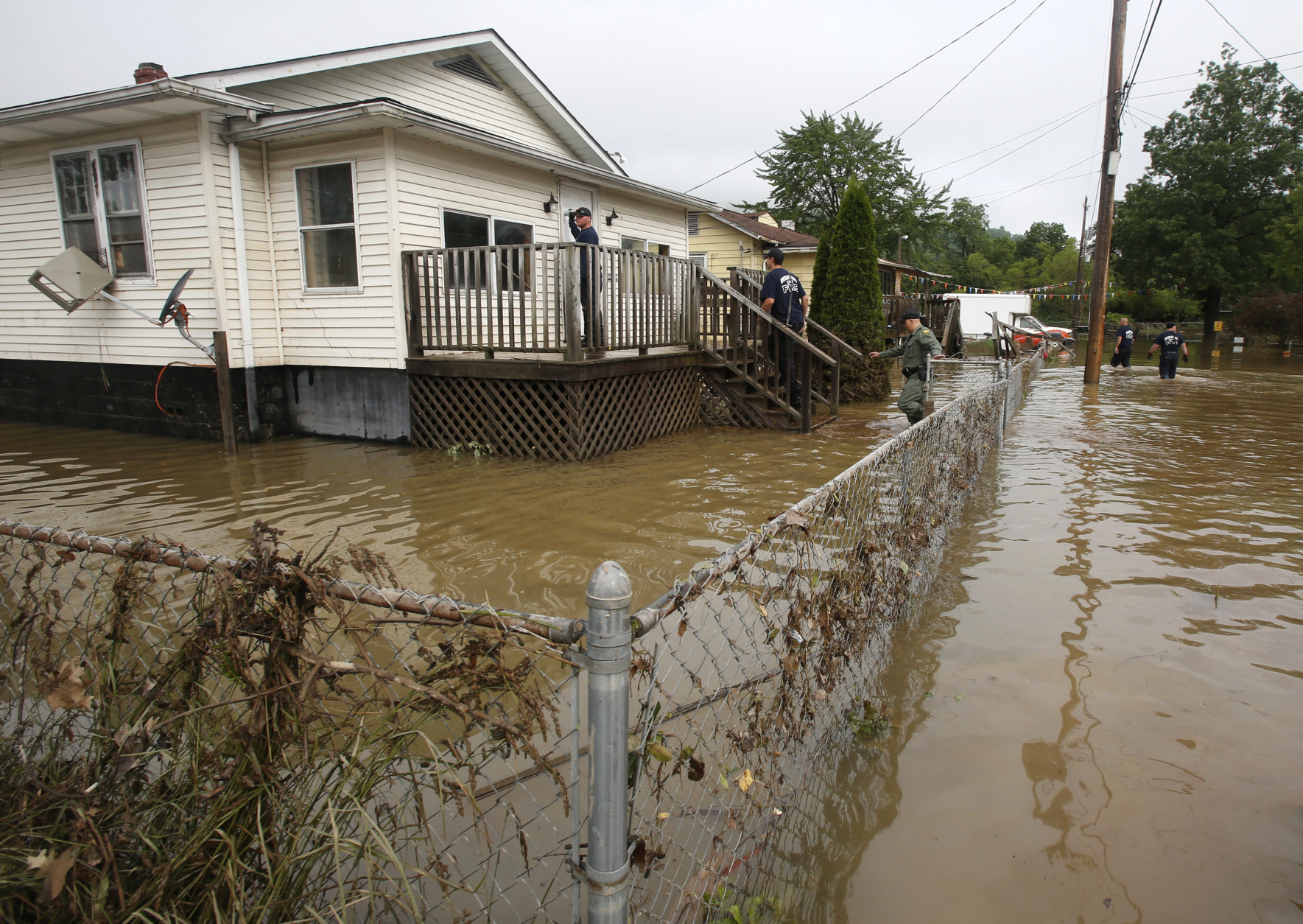 State Police and firefighters search homes along flooded streets in Rainelle, W. Va., Saturday, June 25, 2016. Heavy rains that pummeled West Virginia left multiple people dead, and authorities said Saturday that an unknown number of people in the hardest-hit county remained unaccounted for. (AP Photo/Steve Helber)