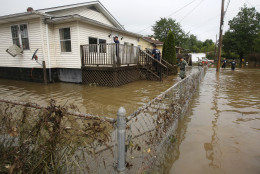 State Police and firefighters search homes along flooded streets in Rainelle, W. Va., Saturday, June 25, 2016. Heavy rains that pummeled West Virginia left multiple people dead, and authorities said Saturday that an unknown number of people in the hardest-hit county remained unaccounted for. (AP Photo/Steve Helber)