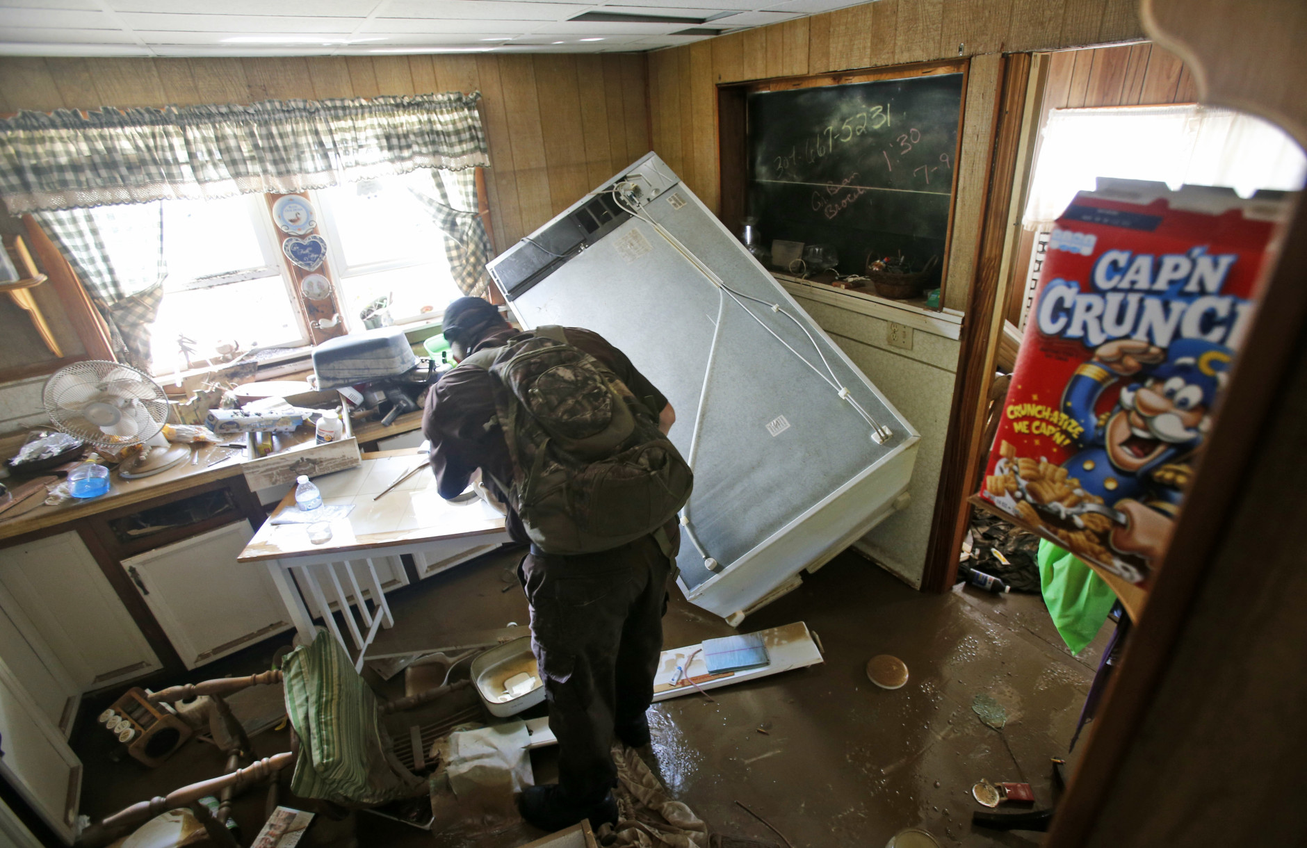 West Virginia Natural Resources police officer Chris Lester searches a flooded home in Rainelle, W. Va., Saturday, June 25, 2016. Heavy rains that pummeled West Virginia left multiple people dead, and authorities said Saturday that an unknown number of people in the hardest-hit county remained unaccounted for. (AP Photo/Steve Helber)