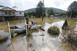 Lt. Dennis Feazell, of the West Virginia Department of Natural Resources, keeps his boat on station as he and a co-worker search flooded homes in Rainelle, W. Va., Saturday, June 25, 2016. Heavy rains that pummeled West Virginia left multiple people dead, and authorities said Saturday that an unknown number of people in the hardest-hit county remained unaccounted for. (AP Photo/Steve Helber)