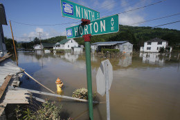 Flooded homes are still surrounded by water in Rainelle, W. Va., Saturday, June 25, 2016.  About 32,000 West Virginia homes and businesses remain without power Saturday after severe flooding hit the state. The West Virginia Division of Homeland Security and Emergency Management also said Saturday that more than 60 secondary roads in the state were closed. (AP Photo/Steve Helber)