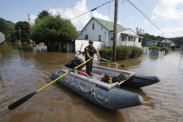 Lt. Dennis Feazell, of the West Virginia Department of Natural Resources, rows his boat as he and a co-worker search flooded homes in Rainelle, W. Va., Saturday, June 25, 2016.  About 32,000 West Virginia homes and businesses remain without power Saturday after severe flooding hit the state. The West Virginia Division of Homeland Security and Emergency Management also said Saturday that more than 60 secondary roads in the state were closed.(AP Photo/Steve Helber)