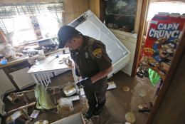 West Virginia Natural Resources police officer Chris Lester searches a flooded home in Rainelle, W. Va., Saturday, June 25, 2016.  About 32,000 West Virginia homes and businesses remain without power Saturday after severe flooding hit the state. The West Virginia Division of Homeland Security and Emergency Management also said Saturday that more than 60 secondary roads in the state were closed.. (AP Photo/Steve Helber)