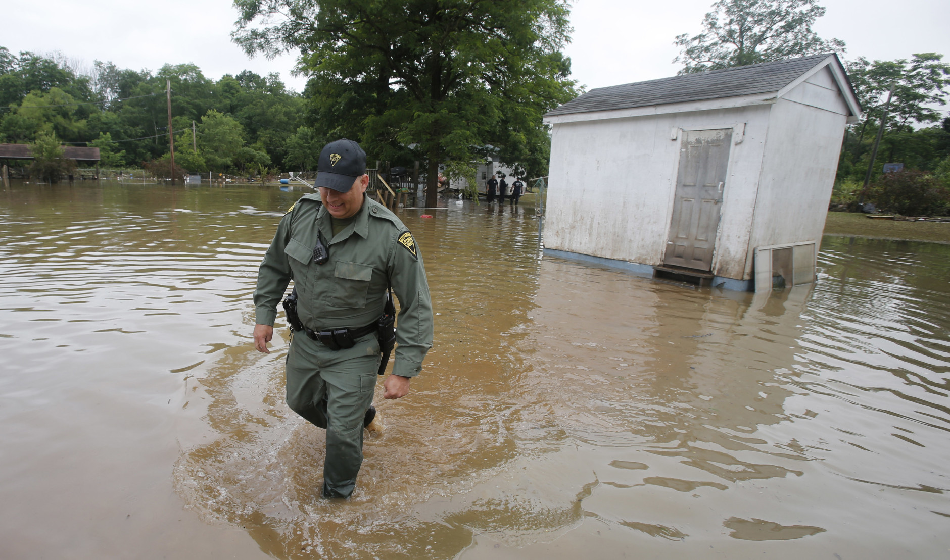 West Virginia State Trooper C.S. Hartman, walks from a shed that he checked out as he and other crews search homes in Rainelle, W. Va., Saturday, June 25, 2016. Heavy rains that pummeled West Virginia left multiple people dead, and authorities said Saturday that an unknown number of people in the hardest-hit county remained unaccounted for. (AP Photo/Steve Helber)
