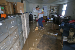 Shane Altzier starts to sweep out the mud from the town utilities office in Rainelle, W. Va., Saturday, June 25, 2016. Heavy rains that pummeled West Virginia left multiple people dead, and authorities said Saturday that an unknown number of people in the hardest-hit county remained unaccounted for .  (AP Photo/Steve Helber)