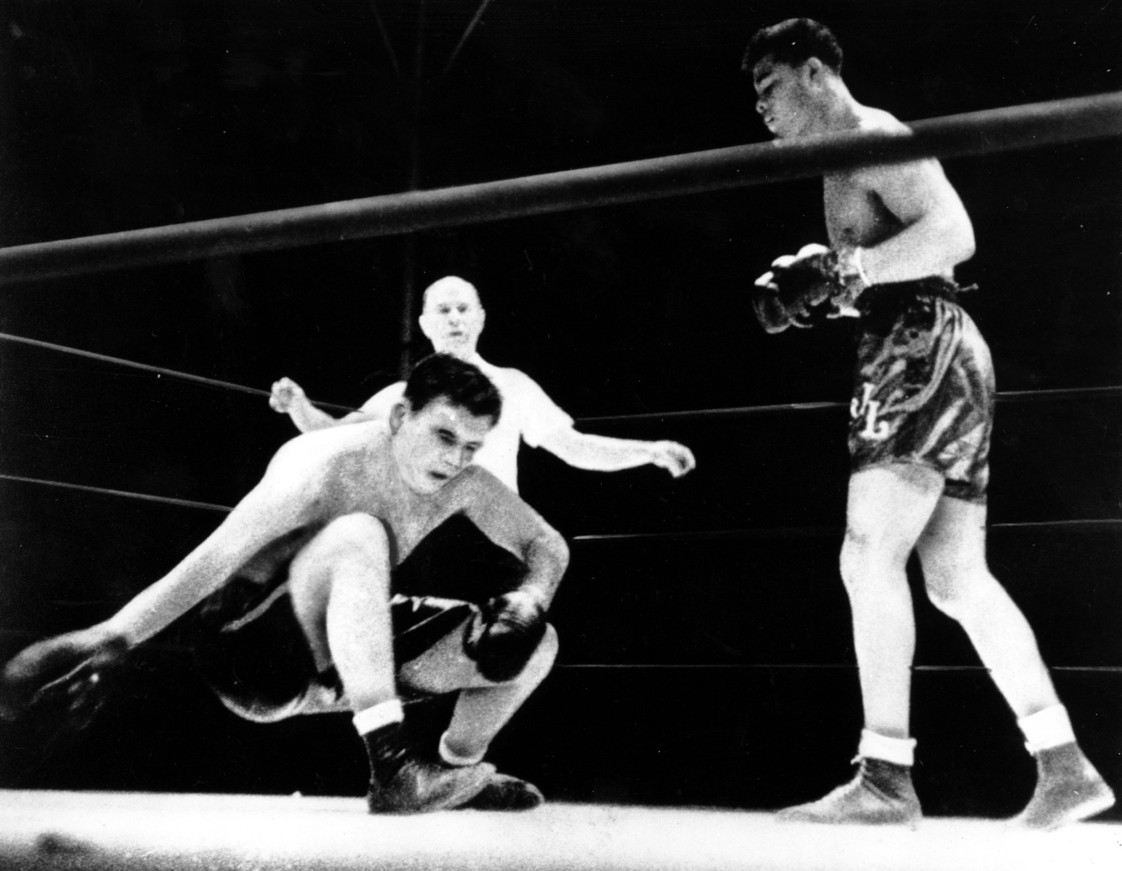 Jim Braddock slumps to the canvas and extends his glove for an easy fall in the championship bout with Joe Louis as Referee Tommy Thomas  watches the outgoing title-holder sink in Chicago, Ill. on June 22, 1937.  (AP Photo)
