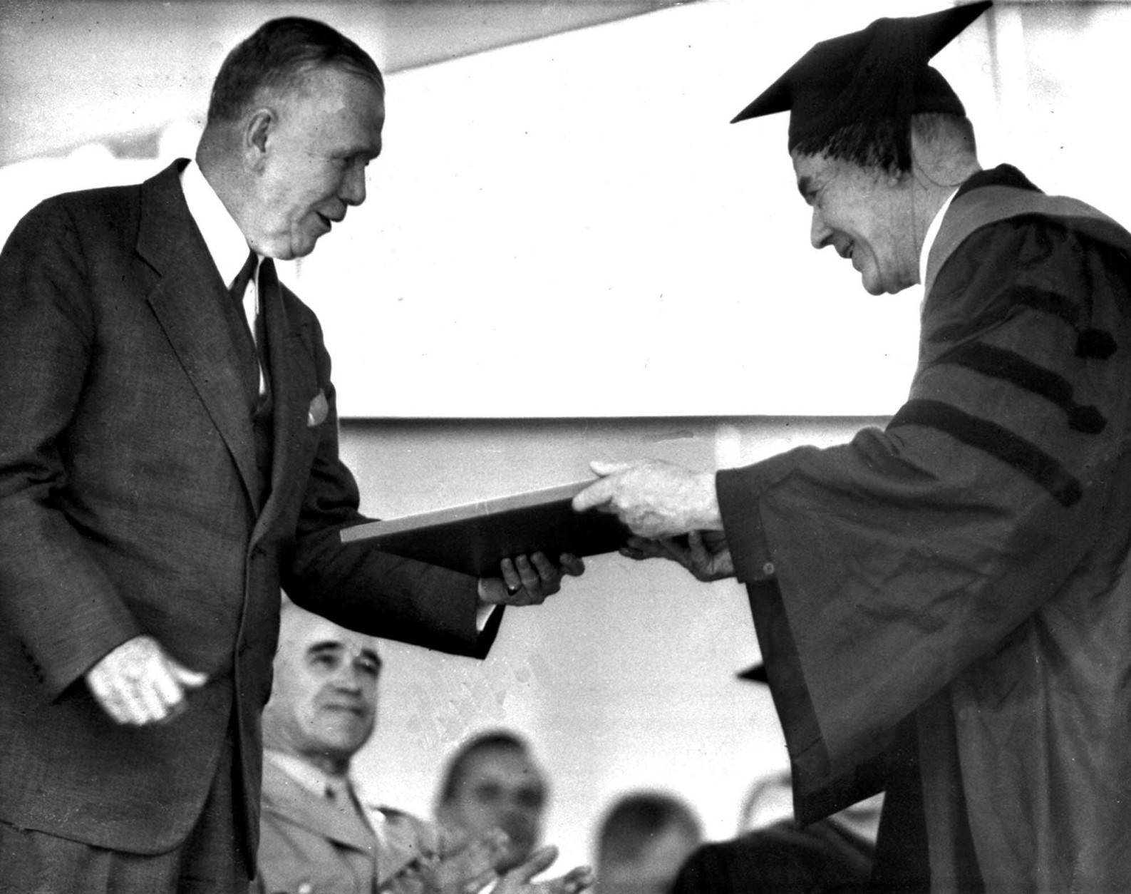 Secretary of State George C. Marshall, left, receives an honorary degree of Doctor of Laws June 5,1947 from Dr. Reginal Fitz, Harvard University marshal.  Presentation to the former Army Chief of Staff took place at university commencement ceremonies at Cambridge, Mass. Gen. Omar N. Bradley, veterans admnistrator, also a degree receipient, is in background next to Marshall. (AP Photo)