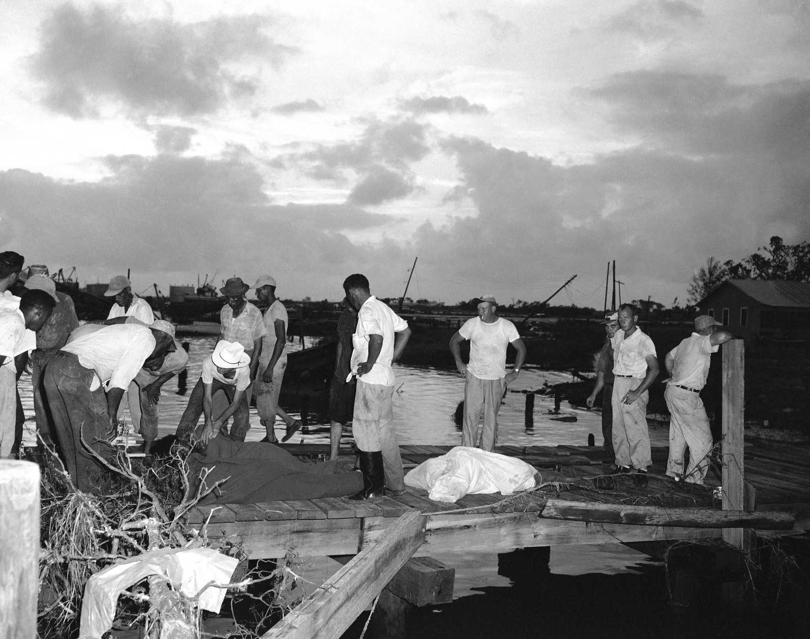A group of people begin the grim task of identifying those killed when hurricane Audrey swept through this small coastal town in Cameron, La., on June 29, 1957. About 50 persons are known dead and about 150 are missing. (AP Photo/Randy Taylor)