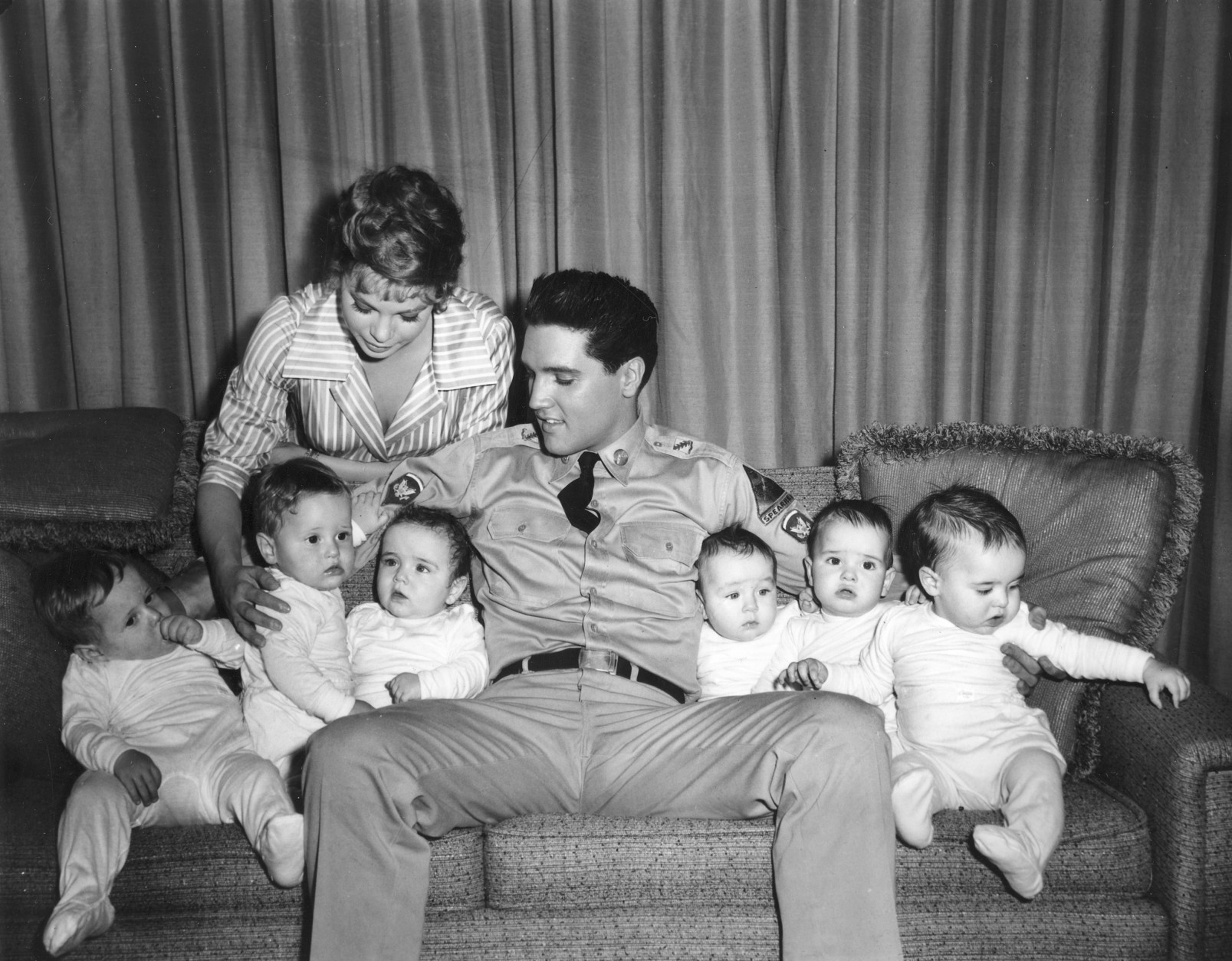 Singer-actor Elvis Presley is shown with six babies who appear in the movie "G.I. Blues" and co-star Juliet Prowse, left, on a set in Hollywood, Ca., on June 27, 1960.  The babies are three sets of twins who double for one another in the movie.  (AP Photo)