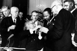 U.S. President Lyndon B. Johnson reaches to shake hands with Dr. Martin Luther King Jr. after presenting the civil rights leader with one of the 72 pens used to sign the Civil Rights Act of 1964 in Washington, D.C., on July 2, 1964.  Surrounding the president, from left, are, Rep. Roland Libonati, D-Ill., Rep. Peter Rodino, D-N.J., Rev. King, Emanuel Celler, D-N.Y., and behind Celler is Whitney Young, executive director of the National Urban League.  (AP Photo)