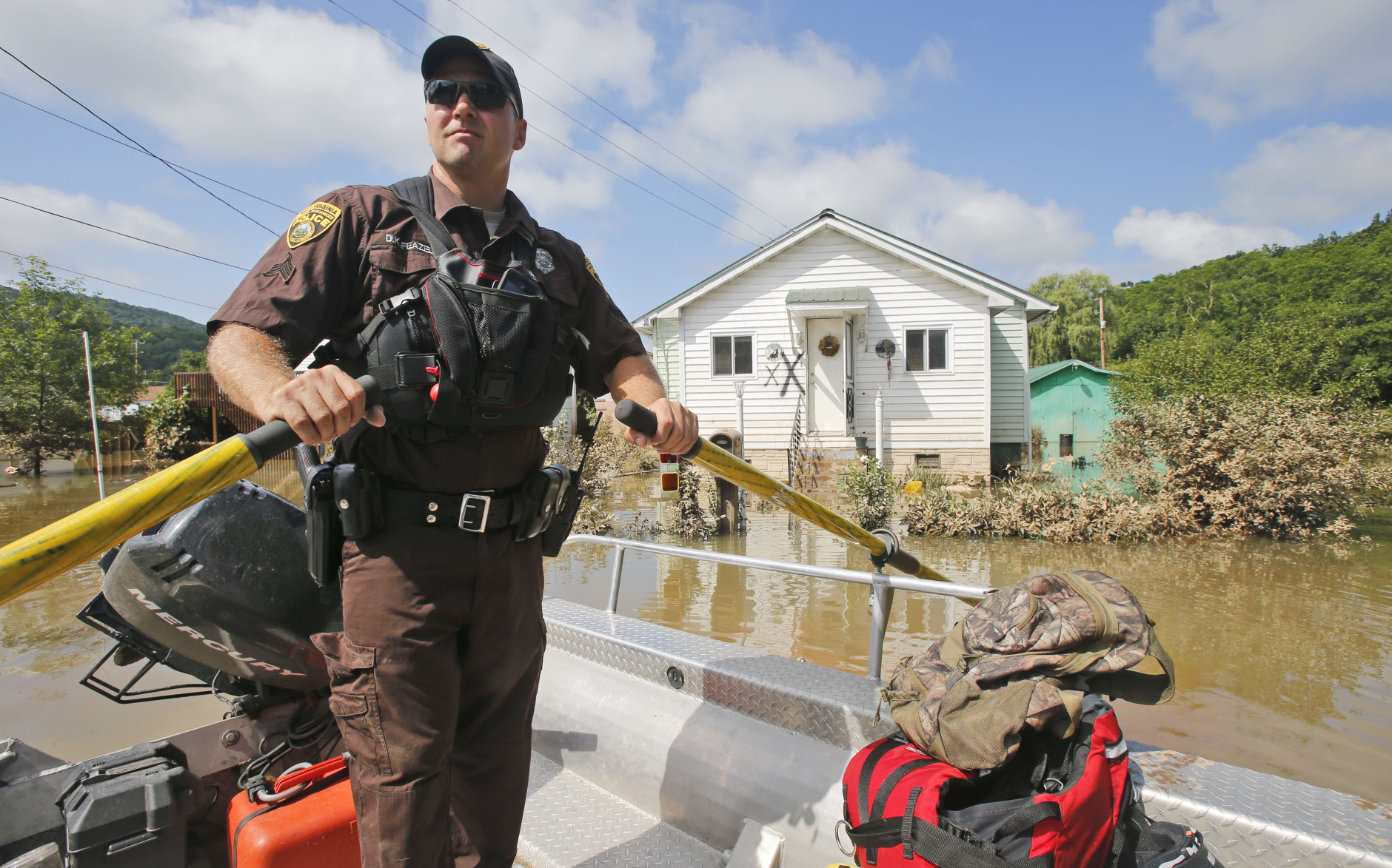 Lt. Dennis Feazell, of the West Virginia Department of Natural Resources, holds his boat at station as he and a co-worker search flooded homes in Rainelle, W. Va., Saturday, June 25, 2016.   There were several fatalities in the area with three people unaccounted for.   (AP Photo/Steve Helber)