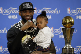 Cleveland Cavaliers' LeBron James answers questions as he holds his daughter Zhuri during a post-game press conference after Game 7 of basketball's NBA Finals Sunday, June 19, 2016, in Oakland, Calif. Cleveland won 93-89. (AP Photo/Eric Risberg)