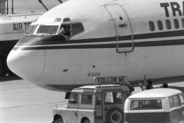 A Shiite Muslim hijacker points his pistol toward an ABC news media crew from the window of the cockpit of the Trans World Airlines jet as the American television crew approaches the jet for an interview at Beirut International Airport, Lebanon, June 19, 1985.  Gunmen hijacked TWA flight 847 carrying 153 people on June 14.  The ordeal lasted 17 days, with one passenger killed.  (AP Photo/Herve Merliac)