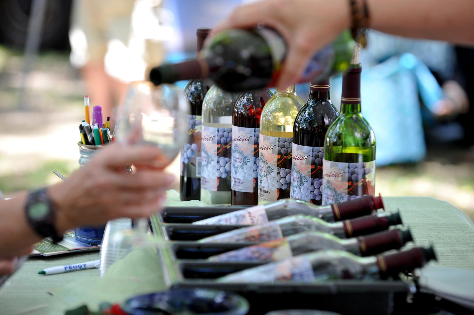 Bottles of wine out for the tasting from Lambert's Vintage Wines are poured during the Food and Wine Festival at Daniels Vineyards in Crab Orchard, W.Va., Saturday, June 20, 2015. (AP Photo/Chris Tilley)