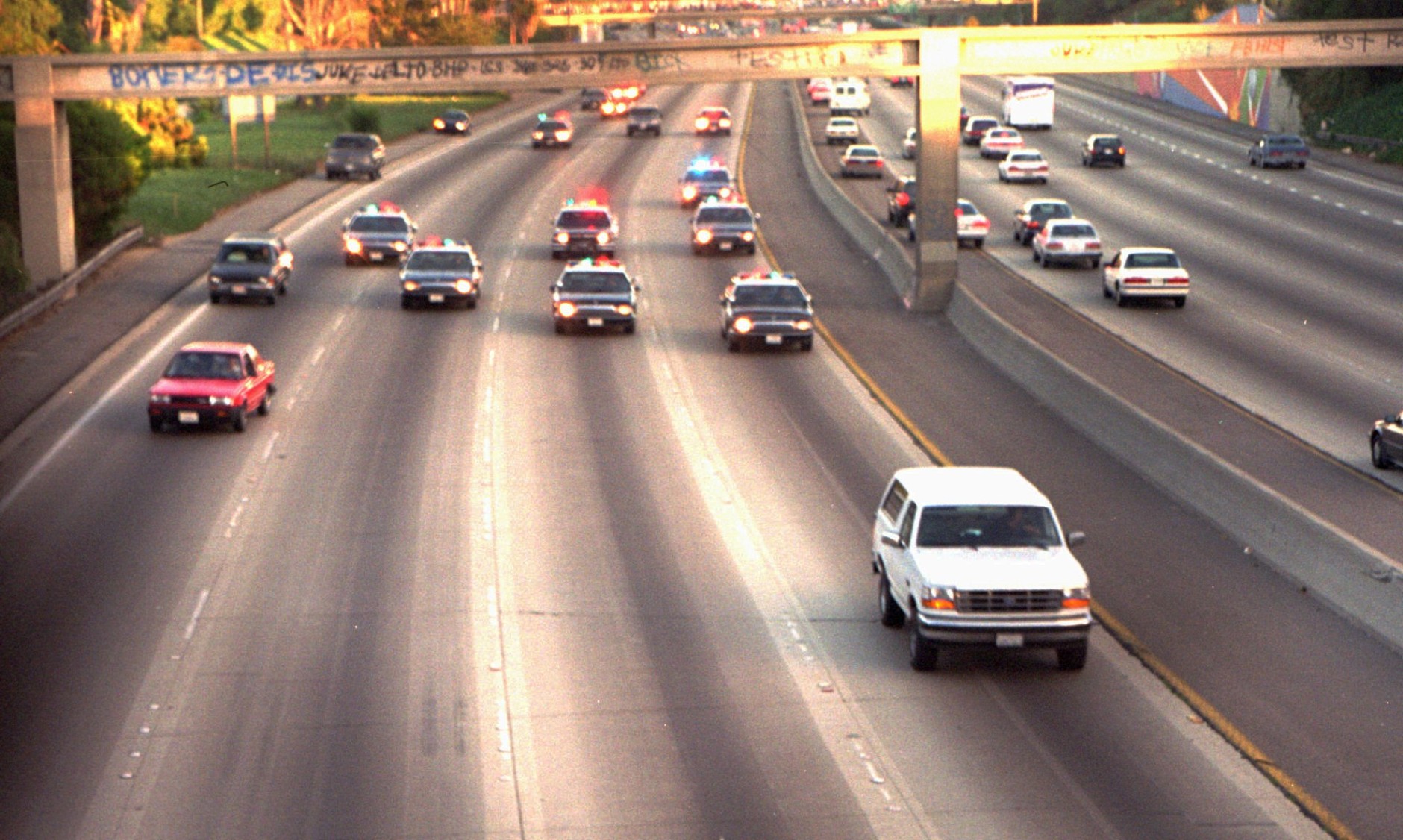 A white Ford Bronco, driven by Al Cowlings and carrying O.J. Simpson, is trailed by police cars as it travels on a southern California freeway on June 17, 1994, in Los Angeles.  Cowlings and Simpson led authorities on a chase after Simpson was charged with two counts of murder in the deaths of his ex-wife and her friend.  (AP Photo/Joseph Villarin)