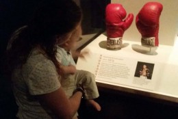 People look at Muhammad Ali's boxing gloves Saturday at the National Museum of American History in D.C. (WTOP/Allison Keyes)