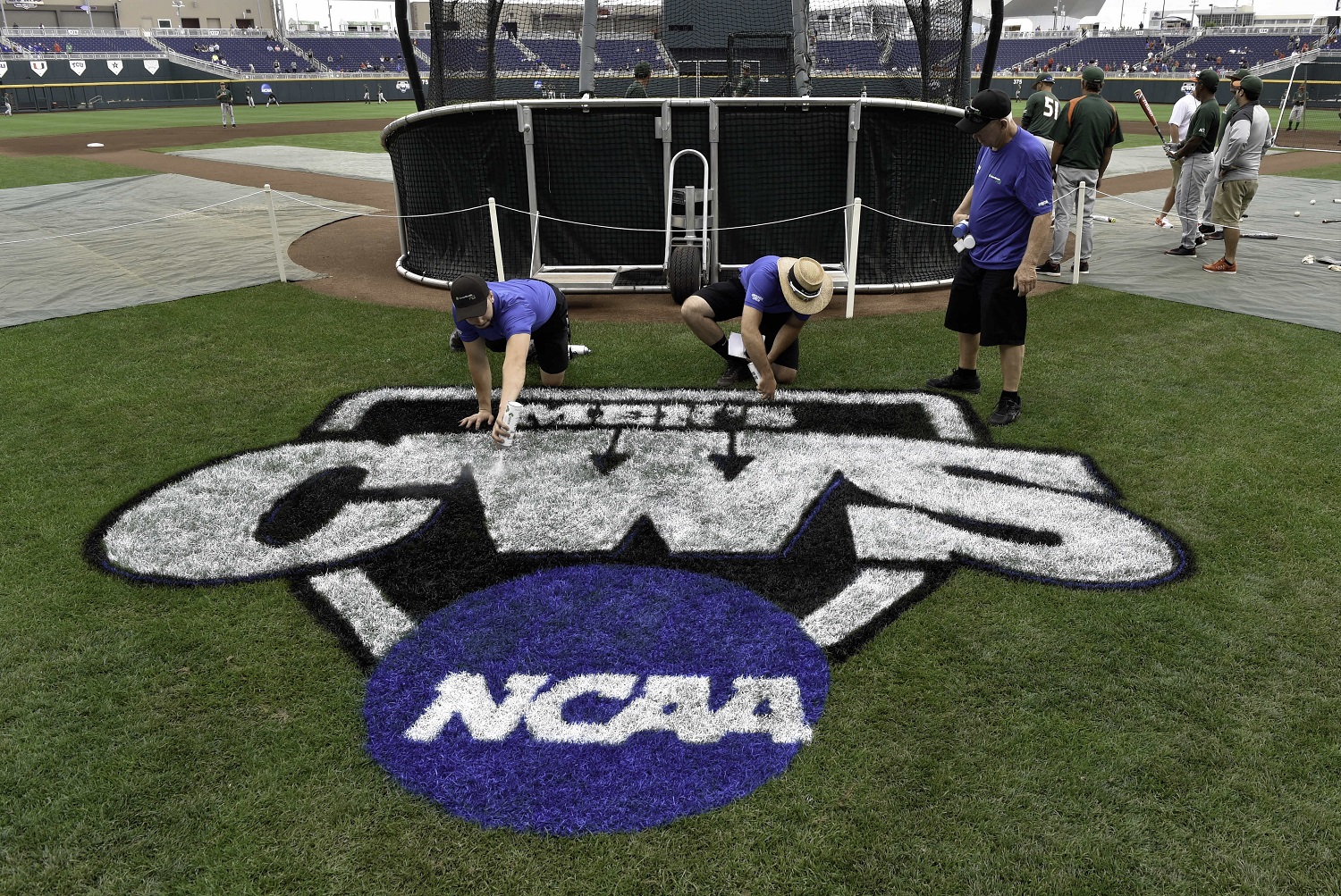 Groundskeepers paint the College World Series logo as Miami players practice at TD Ameritrade Park in Omaha, Neb., Friday, June 12, 2015. The NCAA College World Series baseball tournament starts on Saturday. (AP Photo/Mike Theiler)