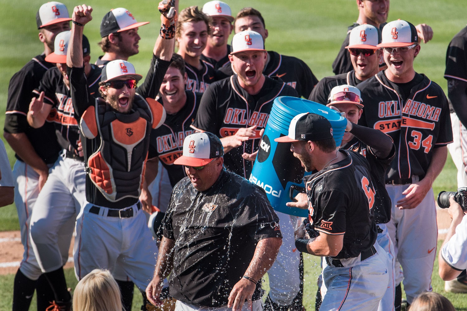Oklahoma State players celebrate a win over South Carolina by dumping the ice cooler on head coach Josh Holliday at an NCAA college baseball tournament super regional game Sunday, June 12, 2016, in Columbia, S.C. (AP Photo/Sean Rayford)