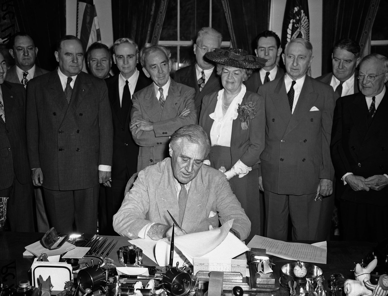 FILE - In this June 22, 1944 file photo, President Franklin D. Roosevelt puts his signature on the G.I. Bill of Rights at the White House in Washington, putting into law the measure for veterans aid.  Looking on from left are: Sen. Bennett Clark, D-Mo.; Rep. J. Harbin Peterson, D-Fla.; Rep. A. Leonard Allen, D-La.; Rep. John Rankin, D-Miss.; Rep. Paul Cunningham, R- Iowa.; Rep. Edith Nourse Rogers, R-Mass.; J.M. Sullivan; Sen. Walter George, D-Ga.; John Steele; and Sen. Robert Wagner, D-N.Y. Sullivan and Steele are American Legion officials who helped sponsor the bill.  (AP Photo/File)