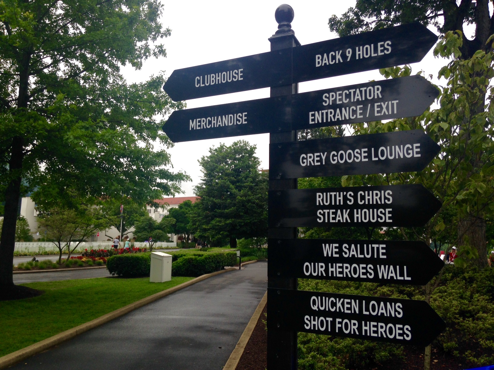 Guests are greeted by signs directing them to the merchandise, heroes wall and back 9 holes of the course. (WTOP/Megan Cloherty)