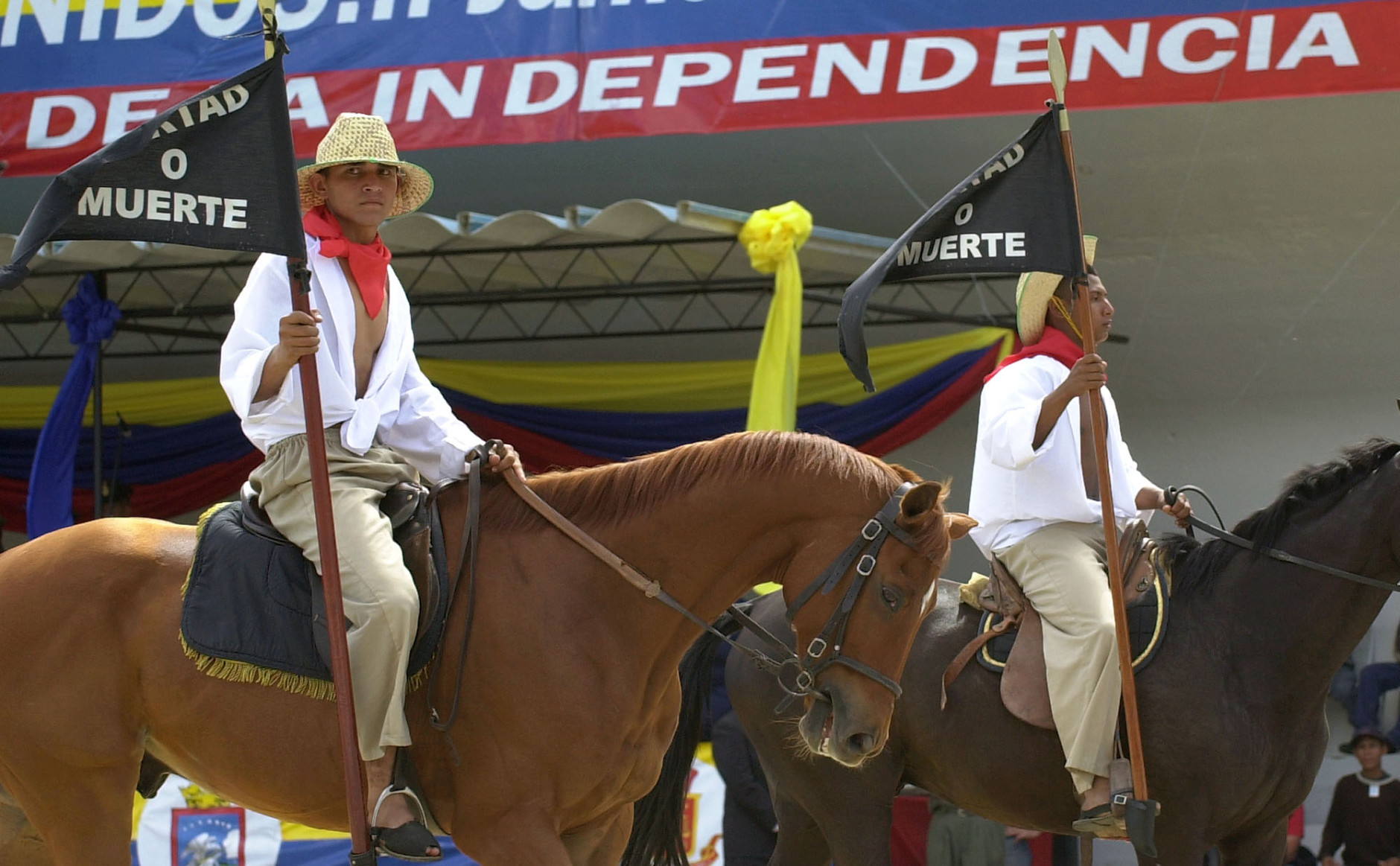 Soldiers dressed as armed peasants who fought for Venezuela's independence ride horses and hold flags reading "Freedom or death" in a military parade to celebrate  Venezuelan Independence Day in Fuerte Tiuna military base in Caracas, Venezuela, Saturday, July 5, 2003. Venezuela was the first South American country to declare its independence from Spain in 1811. (AP Photo/Leslie Mazoch)