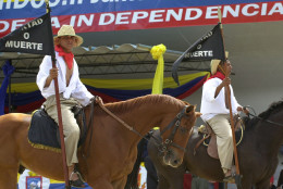 Soldiers dressed as armed peasants who fought for Venezuela's independence ride horses and hold flags reading "Freedom or death" in a military parade to celebrate  Venezuelan Independence Day in Fuerte Tiuna military base in Caracas, Venezuela, Saturday, July 5, 2003. Venezuela was the first South American country to declare its independence from Spain in 1811. (AP Photo/Leslie Mazoch)