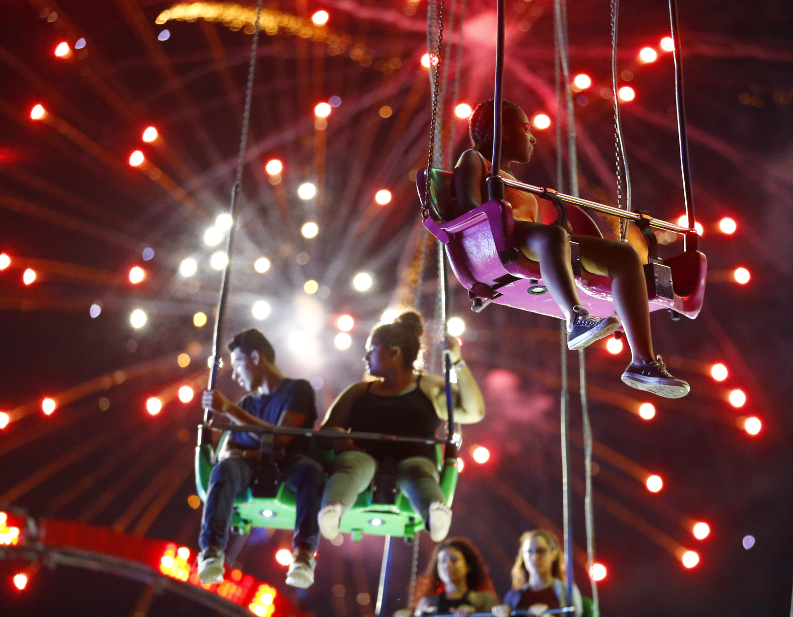 People ride the Sky Flyer at State Fair Meadowlands carnival as fireworks explode, Sunday, July 3, 2016, in East Rutherford, N.J. (AP Photo/Julio Cortez)