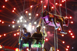 People ride the Sky Flyer at State Fair Meadowlands carnival as fireworks explode, Sunday, July 3, 2016, in East Rutherford, N.J. (AP Photo/Julio Cortez)