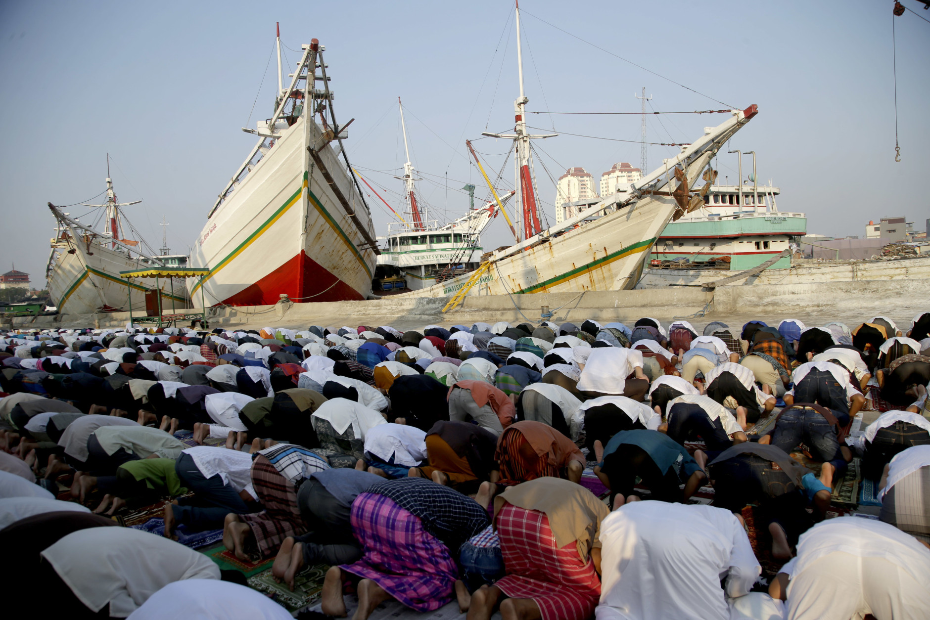 Indonesian Muslim men perform an Eid al-Fitr prayer to mark the end of the holy fasting month of Ramadan at Sunda Kelapa port in Jakarta, Indonesia, Wednesday, July 6, 2016. (AP Photo/Tatan Syuflana)