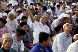 An Indonesian Muslim man uses his mobile phone as he prepares for an Eid al-Fitr prayer to mark the end of the holy fasting month of Ramadan at Sunda Kelapa port in Jakarta, Indonesia, Wednesday, July 6, 2016. (AP Photo/Tatan Syuflana)