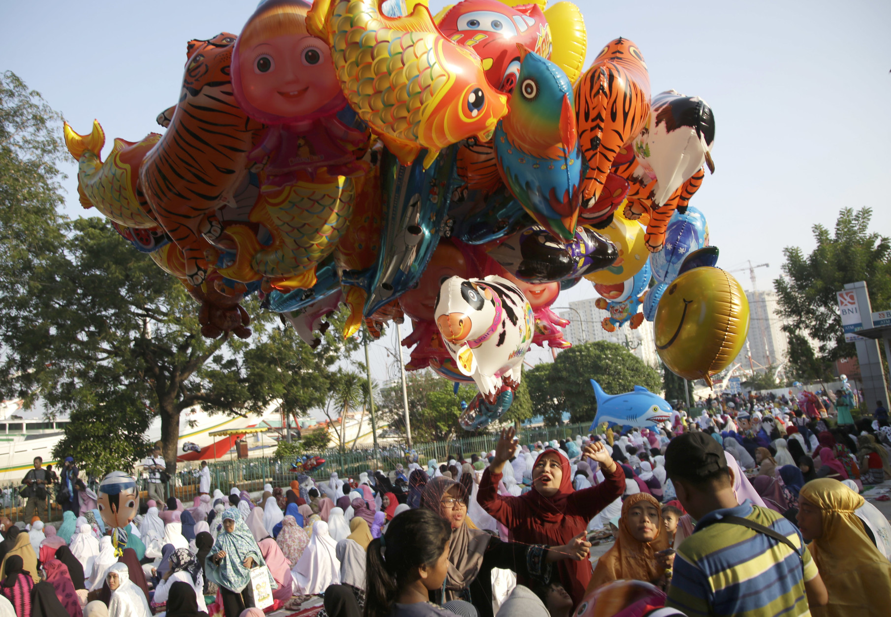 Indonesian Muslim women looks at balloons after an Eid al-Fitr prayer to mark the end of the holy fasting month of Ramadan at Sunda Kelapa port in Jakarta, Indonesia, Wednesday, July 6, 2016. (AP Photo/Tatan Syuflana)