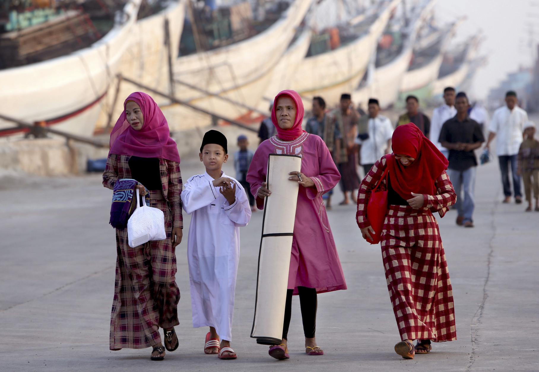 Indonesian Muslim arrive for an Eid al-Fitr prayer to mark the end of the holy fasting month of Ramadan at Sunda Kelapa port in Jakarta, Indonesia, Wednesday, July 6, 2016. (AP Photo/Tatan Syuflana)