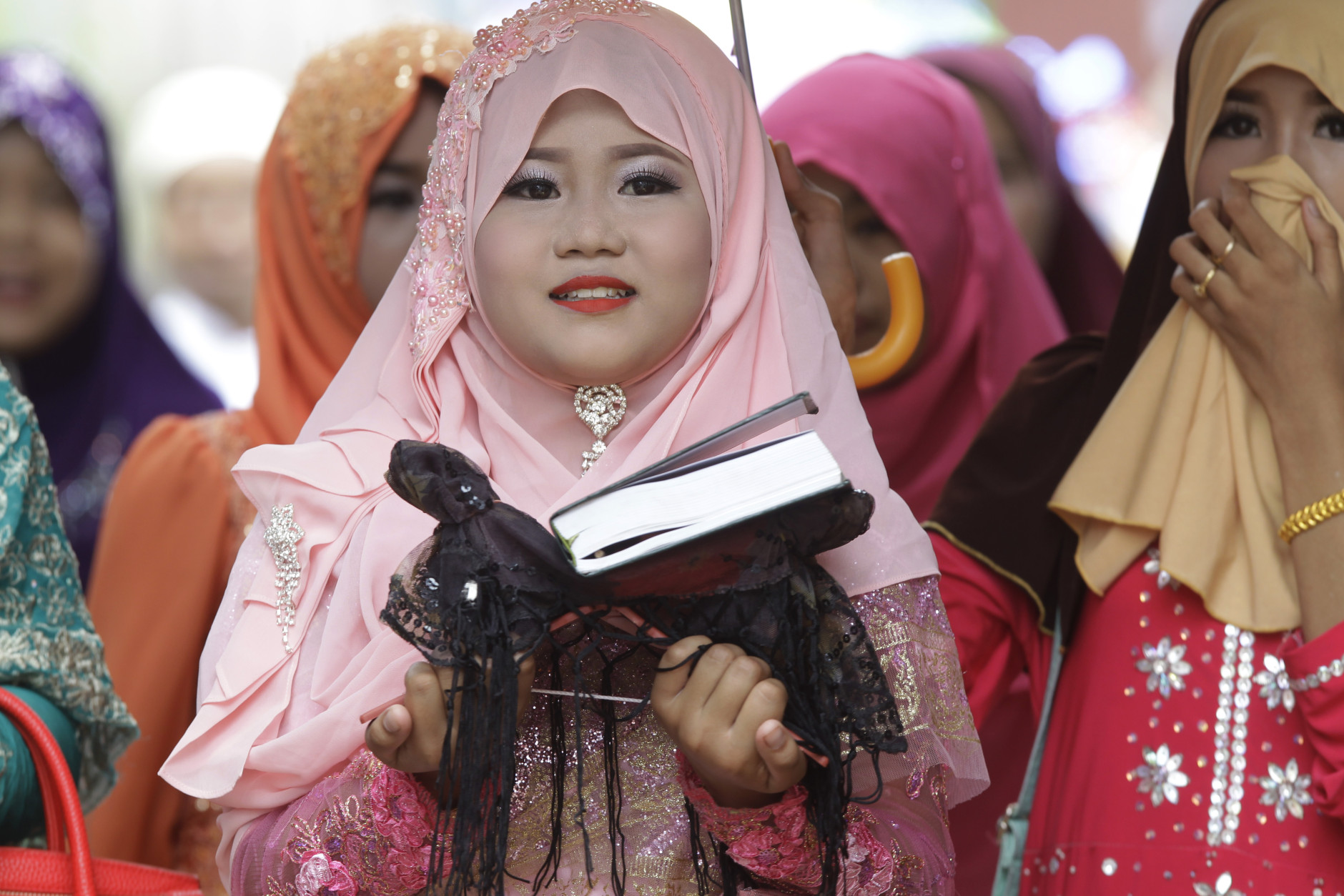 A girl carries a Quran during Eid al-Fitr prayers along the Mekong river of Tanong, northeast of Phnom Penh, Cambodia, Wednesday, July 6, 2016.  The Eid al-Fitr celebrations mark the end of the Muslim holy fasting month of Ramadan. (AP Photo/Heng Sinith)