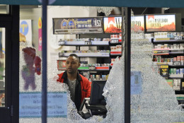 A clerk looks at broke windows shot out at a store in downtown Dallas, Friday, July 8, 2016.  Snipers opened fire on police officers in the heart of Dallas during protests over two recent fatal police shootings of black men.(AP Photo/LM Otero)