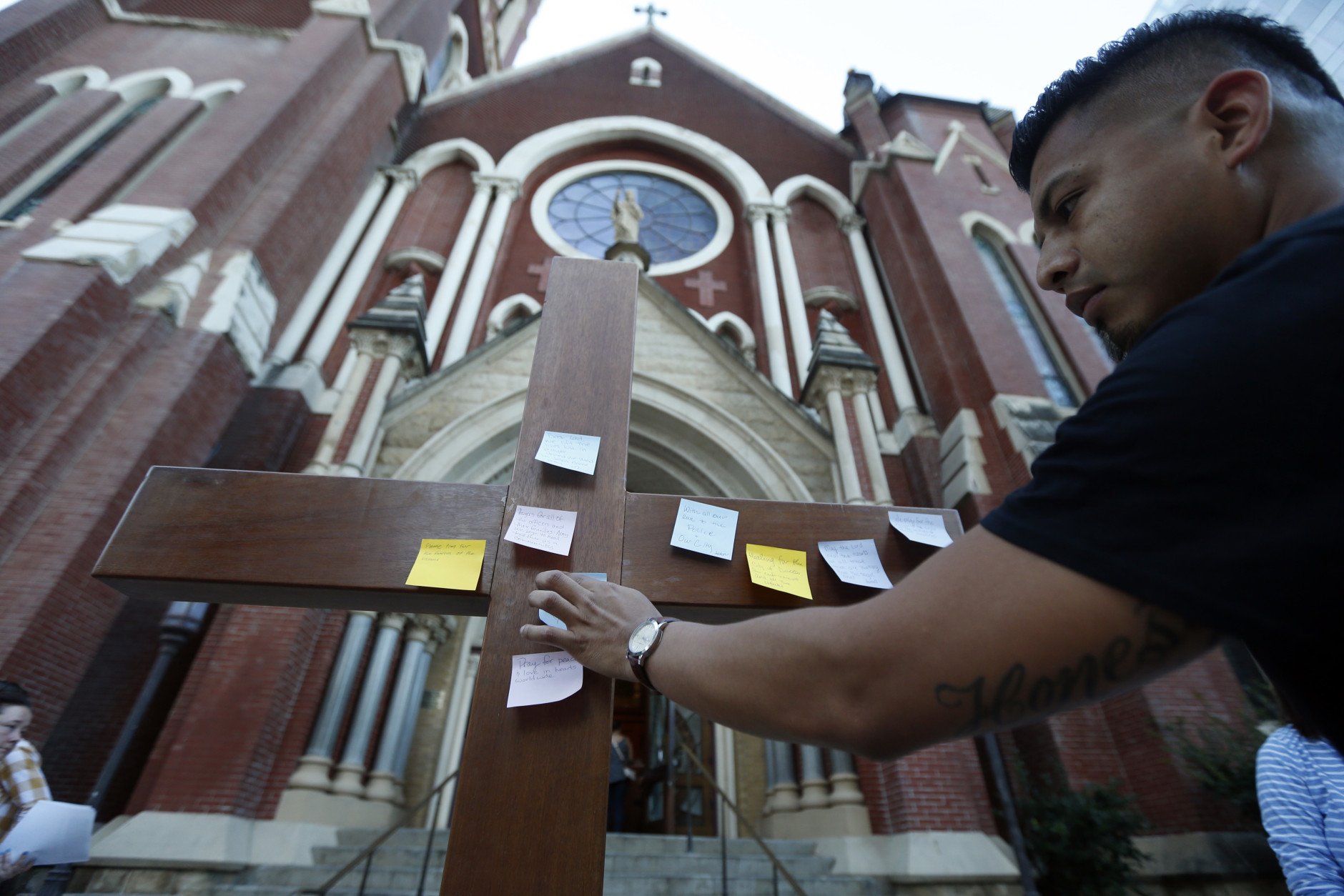 Misael Gonzalez, of Dallas, places a prayer onto a crucifix before entering a prayer vigil Friday, July 8, 2016, in Dallas at Cathedral Guadalupe, in memory of the Dallas police officers who were slain Thursday. (AP Photo/Gerald Herbert)