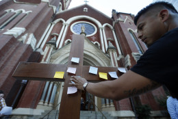 Misael Gonzalez, of Dallas, places a prayer onto a crucifix before entering a prayer vigil Friday, July 8, 2016, in Dallas at Cathedral Guadalupe, in memory of the Dallas police officers who were slain Thursday. (AP Photo/Gerald Herbert)