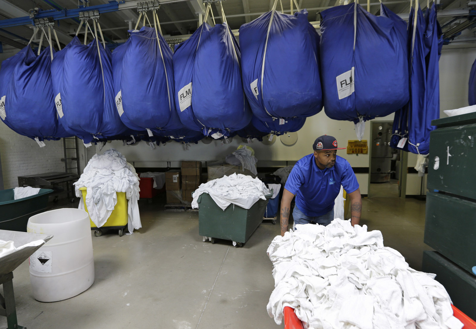 In a Friday, June 24, 2016 photo, Chris Brown moves laundry at the Evergreen Cooperative Laundry in Cleveland. Donald Trump's effort to unite a splintered Republican Party around his candidacy is about to take center stage in a city that is itself deeply fractured. Brown, a lifelong Clevelander, admits he was part of the problem in his younger days. Caught selling drugs, he went to prison for three years. Afterward, getting by was a struggle until he started working at the commercial laundry four years ago.   (AP Photo/Tony Dejak)