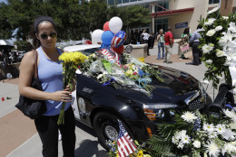 A woman places flowers on a make-shift memorial at the Dallas police headquarters, Friday, July 8, 2016, in Dallas. Five police officers are dead and several injured following a shooting in downtown Dallas Thursday night. (AP Photo/Eric Gay)