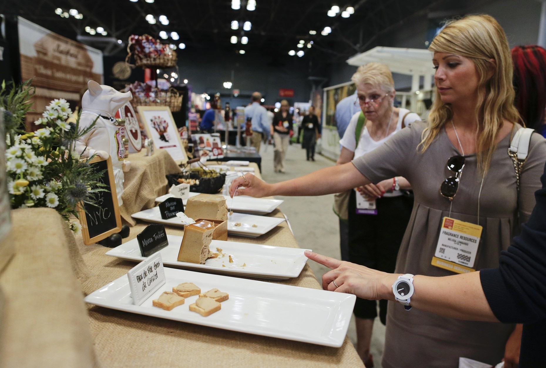 CORRECTS FIGURES- Convention goers sample a variety of pates at the Summer Fancy Food Show specialty food convention, Tuesday, July 1, 2014, in New York. About 90,000 pounds of delicacies were donated and distributed to food pantries across the five boroughs. (AP Photo/Julie Jacobson)
