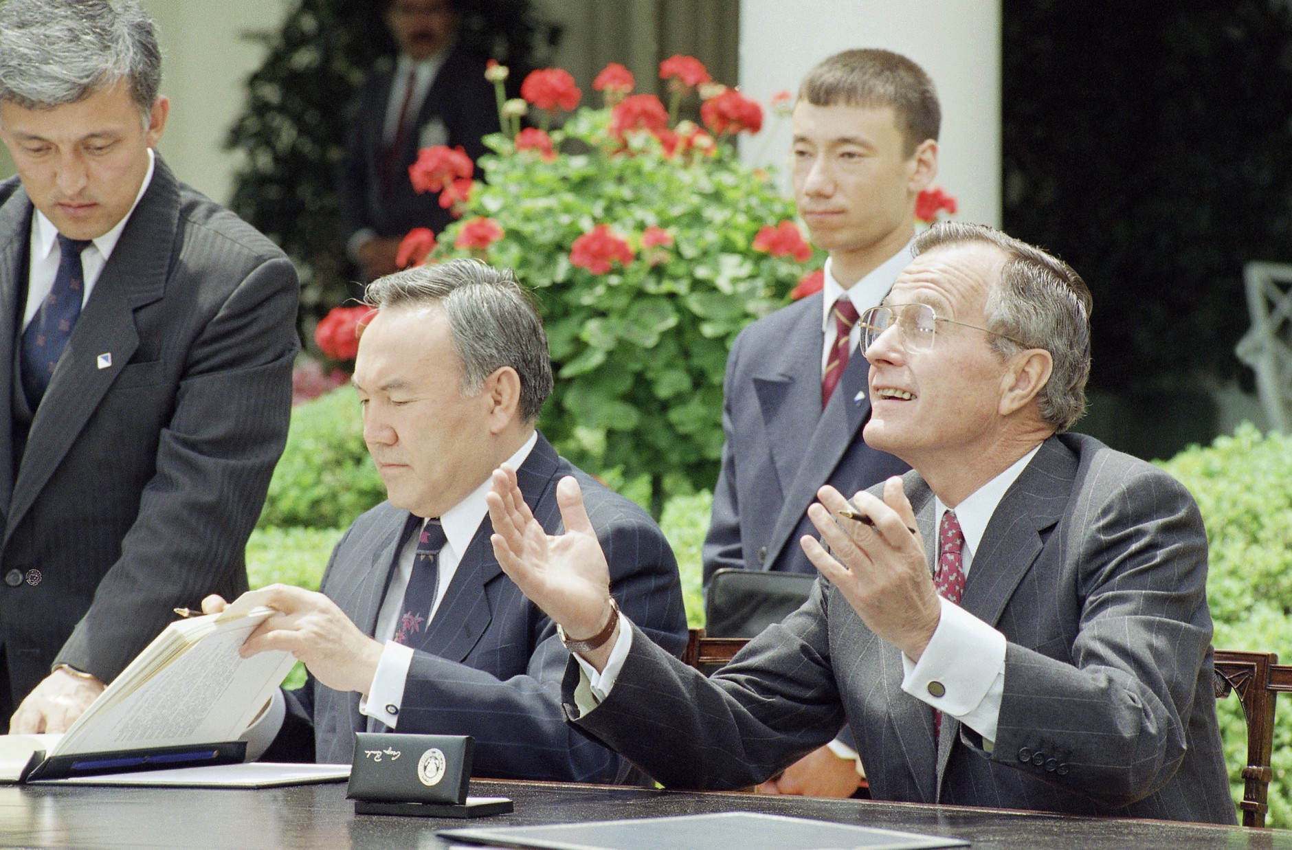 U.S. President George H. Bush gestures while President Nursultan Nazarbayev of Kazakhstan reads his papers after signing a nonproliferation treaty in the Rose Garden of the White house in Washington, Tuesday, May 19, 1992. President Nazarbayev said Tuesday that his country will adhere to agreements barring the transfer of nuclear weapons and their technology. (AP Photo/Ron Edmonds) 