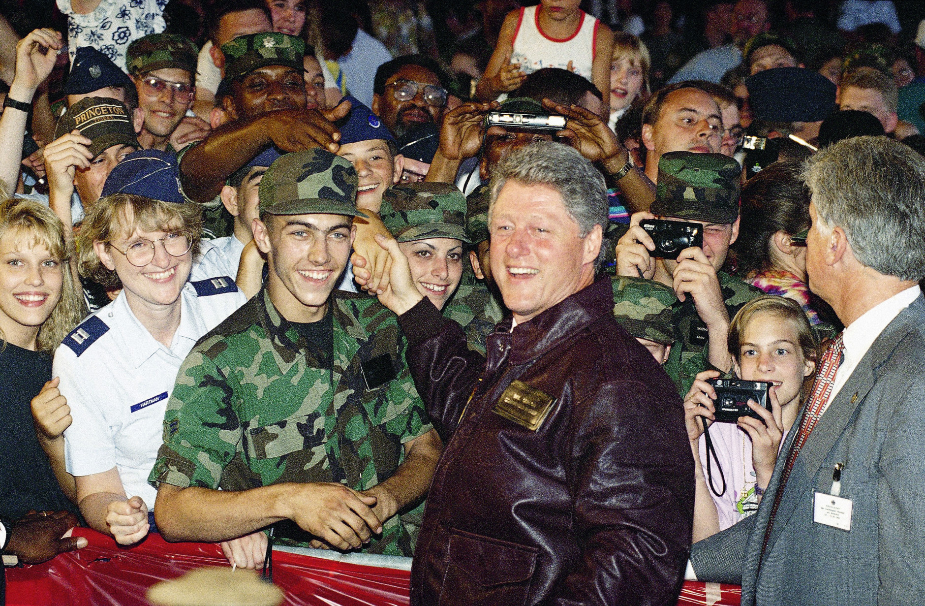 Wearing a leather jacket inscribed with his name and title and given to him by local personnel, President Bill Clinton meets with members of the American Armed Forces gathered at the Ramstein Air Force Base in Berlin, July 11, 1994. In a speech, President Bill Clinton promised there would be no further cuts in defense spending and that U.S. troops would remain in Europe. (AP Photo/Marcy Nighswander)