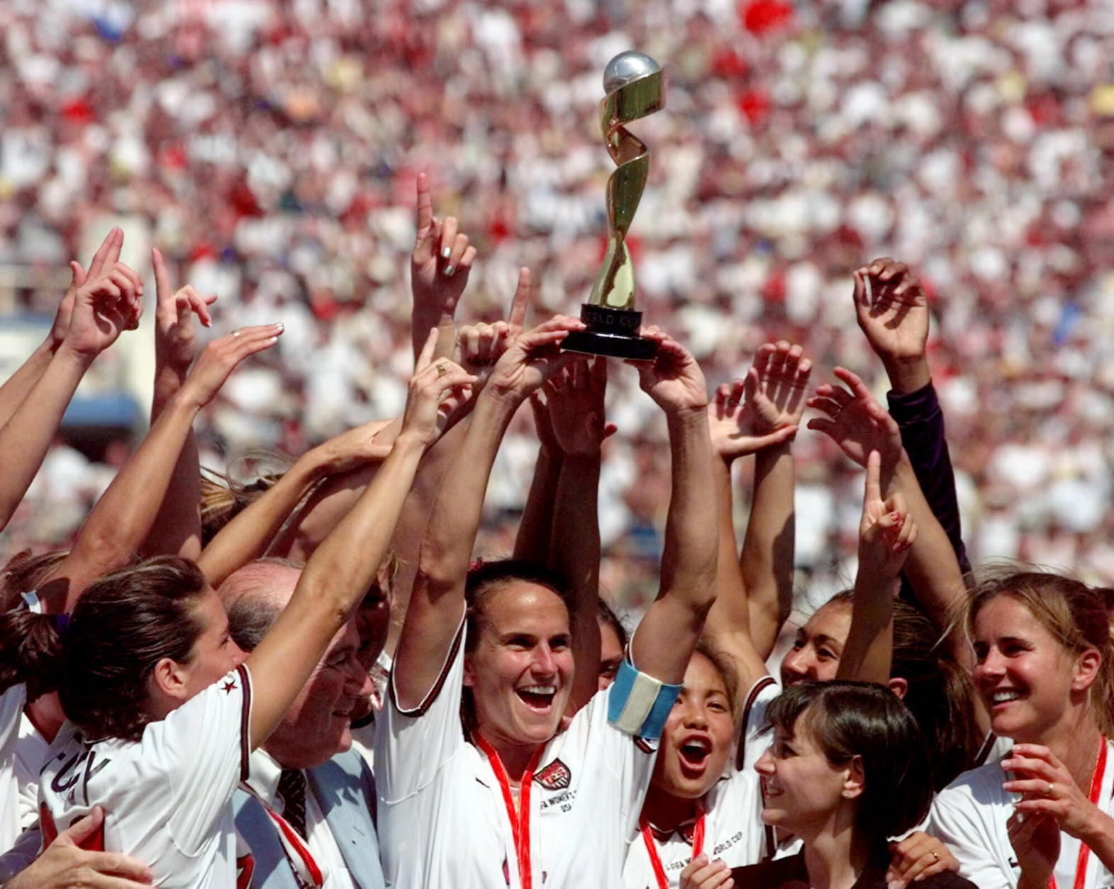 ADVANCE FOR WEEKEND EDITIONS, JUNE 11-12 - FILE - In this July 10, 1999 file photo, the United States soccer team captain Carla Overbeck, center, the U.S. team and FIFA President Sepp Blatter, left of Overbeck, celebrate with the trophy after defeating China in a 5-4 in a penalty shootout in the Women's World Cup Final at the Rose Bowl in Pasadena, Calif. They were pioneers, and they were rock stars. A dozen years later, they remain the most famous women's team in U.S. sports. (AP Photo/Michael Caulfield, File)