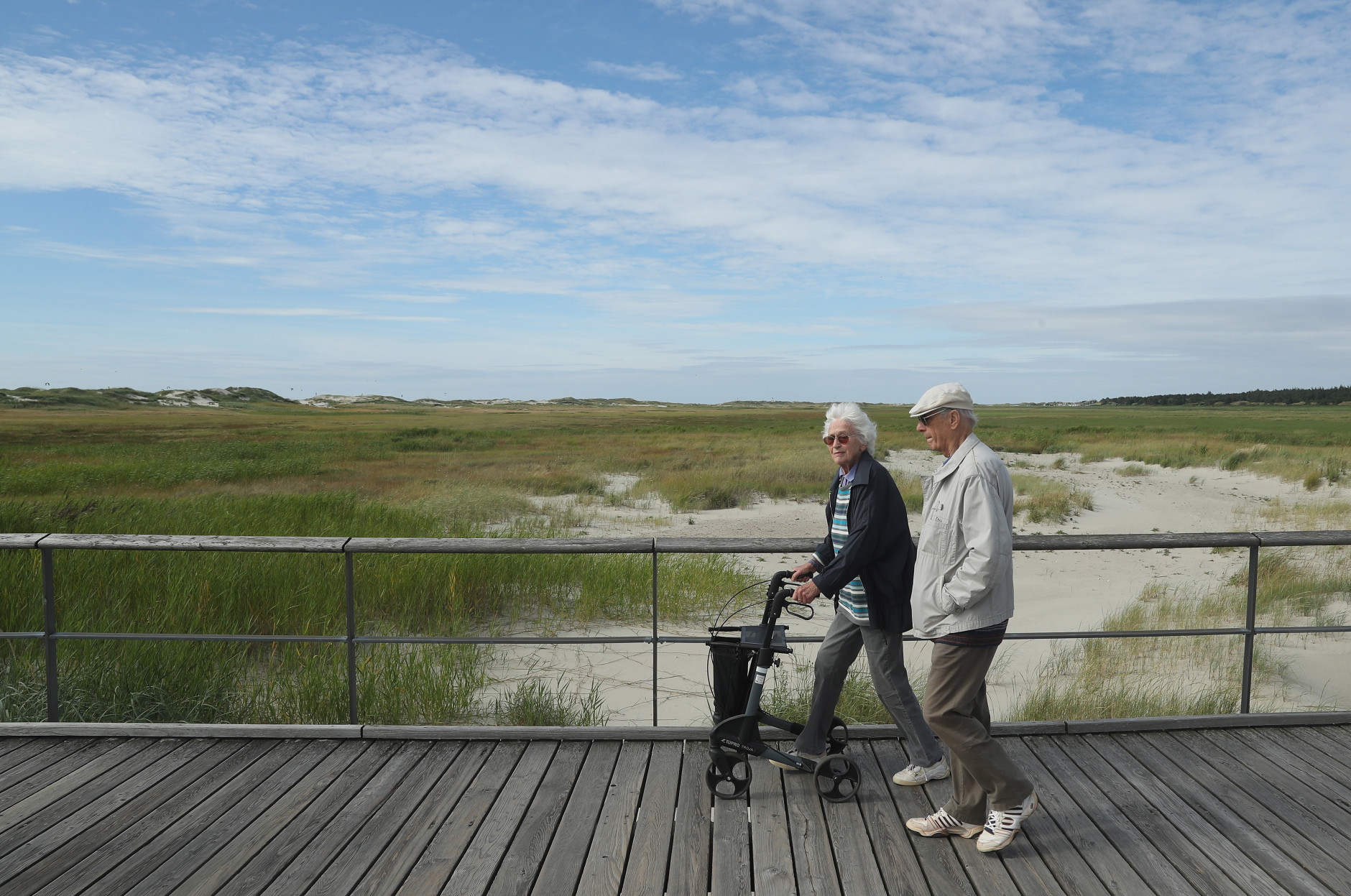 ST PETER-ORDING, GERMANY - JULY 18:  An elderly couple, who said they did not mind being photographed, walk along a wooden walkway that crosses protected dunes and salt marshes on July 18, 2016 at Sankt-Peter-Ording, Germany. Sankt-Peter-Ording is among the top destinations for vacationers along Germany's North Sea coast. Many Germans, unsettled by the recent terror attacks in countries like France and Turkey, are choosing to vacation in Germany this summer.  (Photo by Sean Gallup/Getty Images)