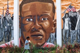 A person passes in front of a Freddie Gray mural in his Sandtown neighborhood of Baltimore. (WTOP/Kate Ryan)
