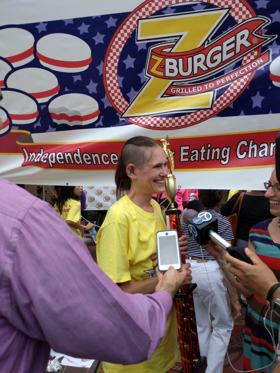 Winner Molly Schuyler is all smiles after topping her previous record, eating 28 burgers for this year's competition. (WTOP/Ginger Whitaker)