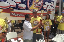 Munchin’ Mike Longo claims his prize for downing 11 burgers in 10 minutes. (WTOP/Mike Murillo)
