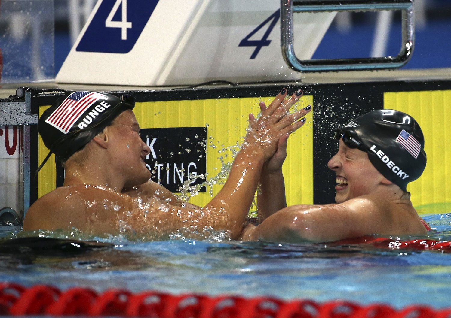 Katie Ledecky of the U.S. high fives team mate Cierra Runge after Ledecky set a new world record in her women's 400m freestyle final at the Pan Pacific swimming championships in Gold Coast, Australia, Saturday, Aug. 23, 2014. Ledecky set a new world record of 3:58.37 ahead of Runge and Lauren Boyle of New Zealand.(AP Photo/Rick Rycroft)