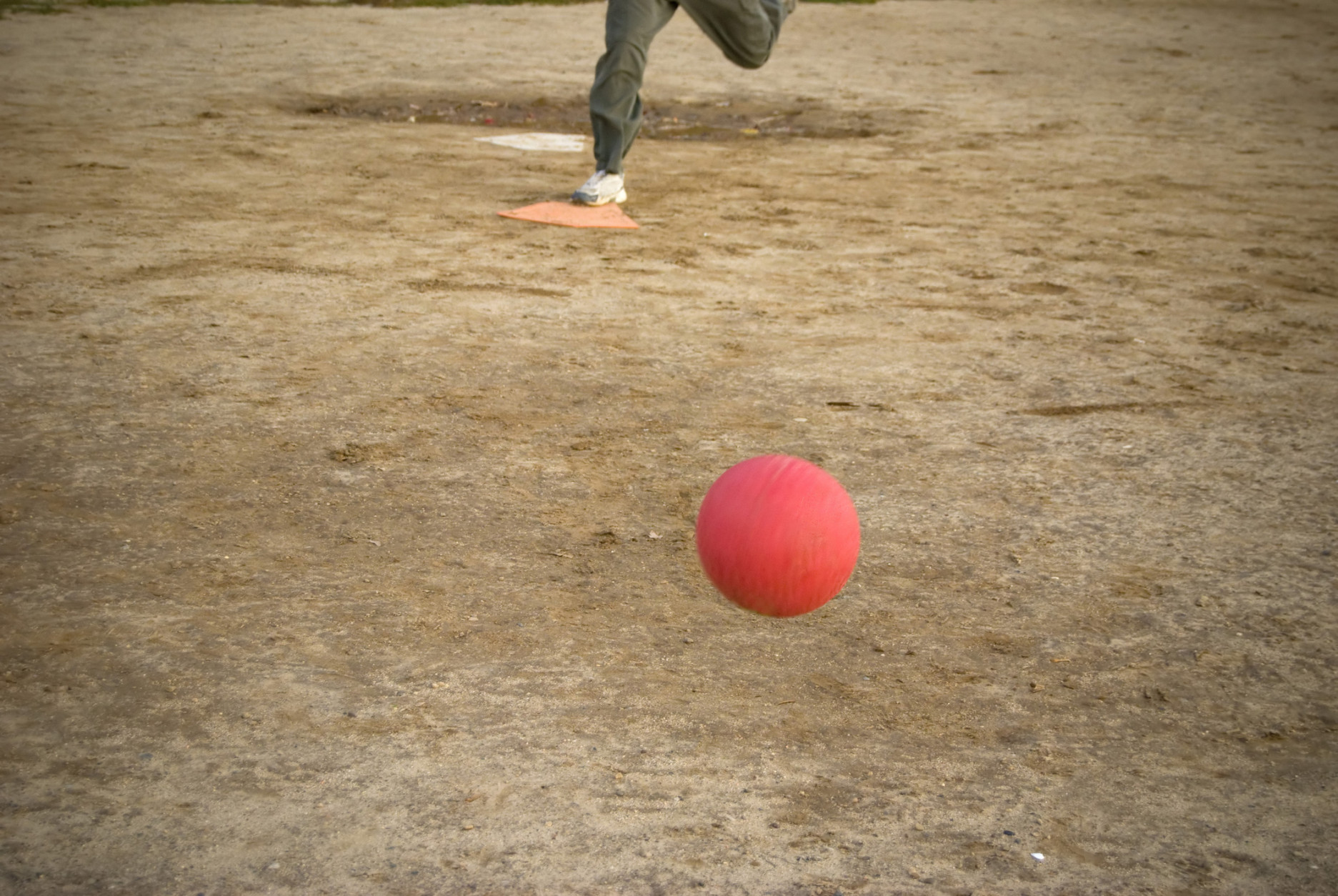 A red kickball rolls toward home plate after it is pitch - the person pictured here on plate is approaching the kick. (Thinkstock)