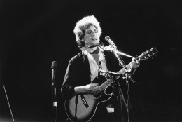 This is an undated photo of singer-songwriter Bob Dylan as he plays his acoustic guitar with his harmonica at an unknown location.  (AP Photo)
