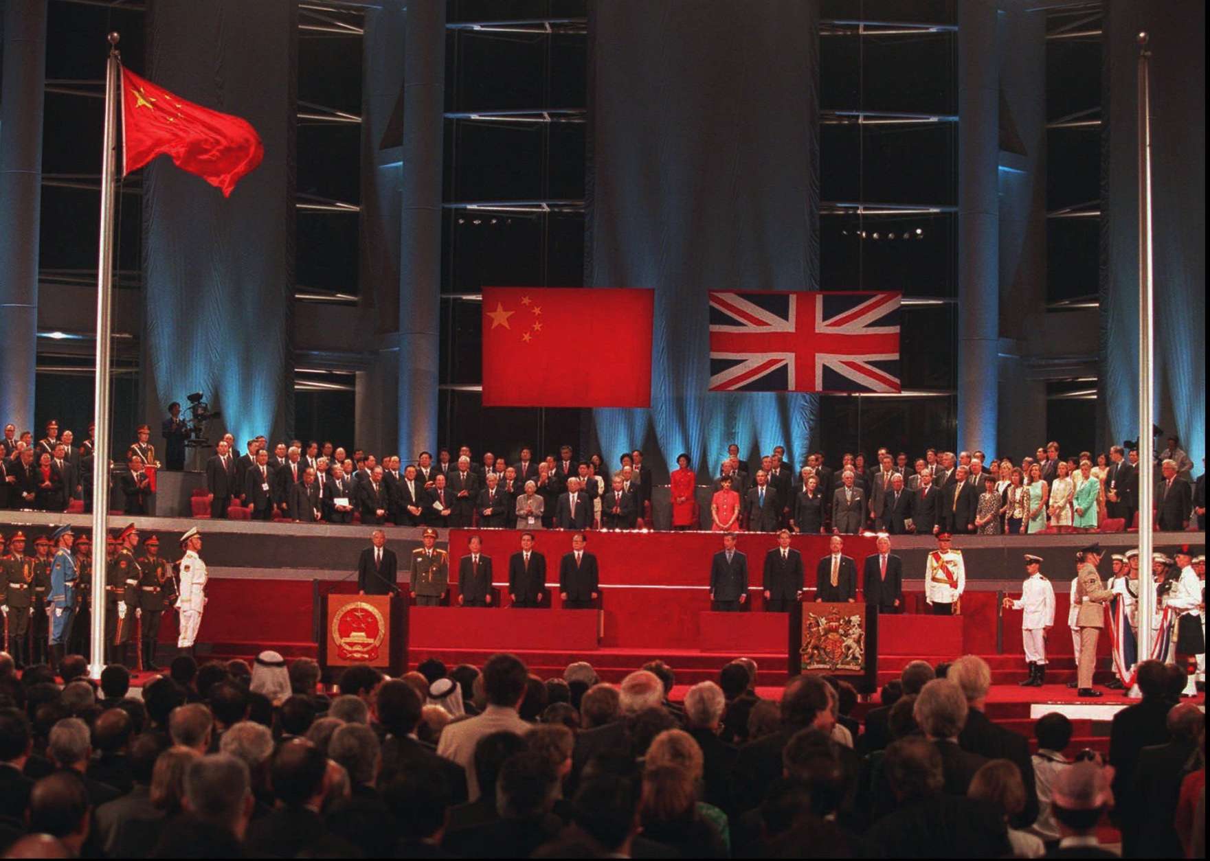 World dignitaries and other guests to the Hong Kong handover ceremony stand and watch the Chinese flag, left, flying after the Union Jack was lowered at the Hong Kong Convention Center Tuesday, July 1, 1997. (AP Photo/Kimimasa Mayama, Pool)
